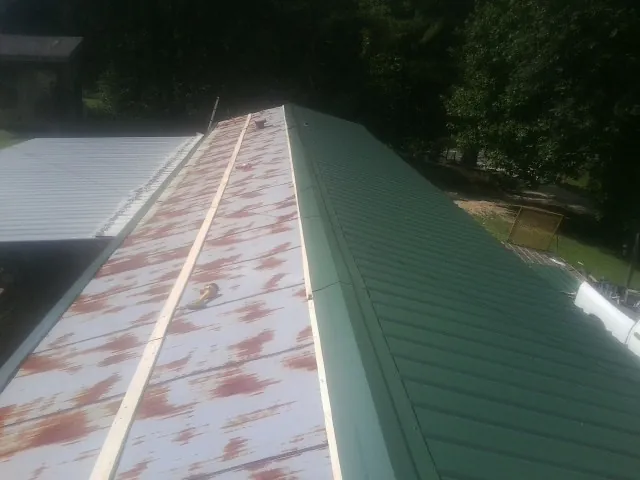 Old rusted panels beside newly installed green metal roofing — Wind Damage Roof Repair by Roofing Brothers in Lulu