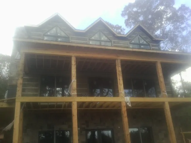 Dormers and porch framing on a large log home under construction — Roof Coating work by our crew in Lulu