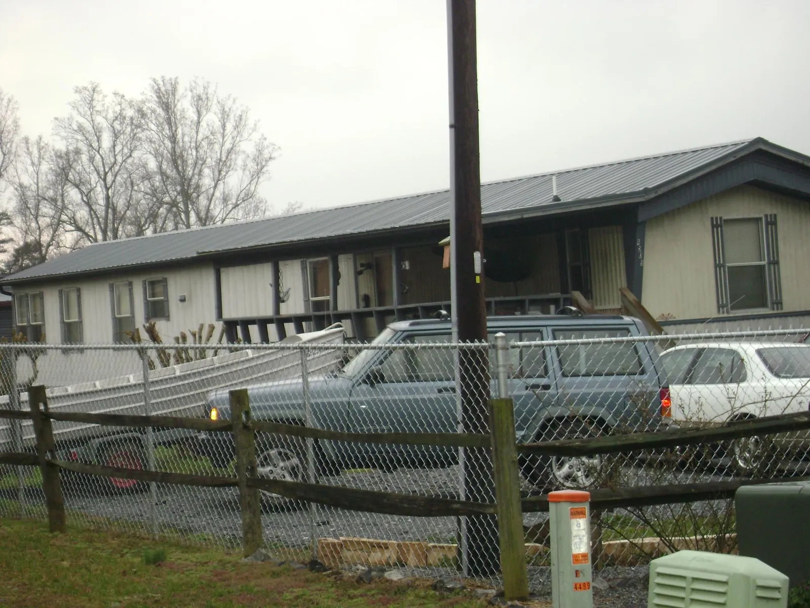 Dark metal roof on a long single story building behind a chain link fence in Lulu