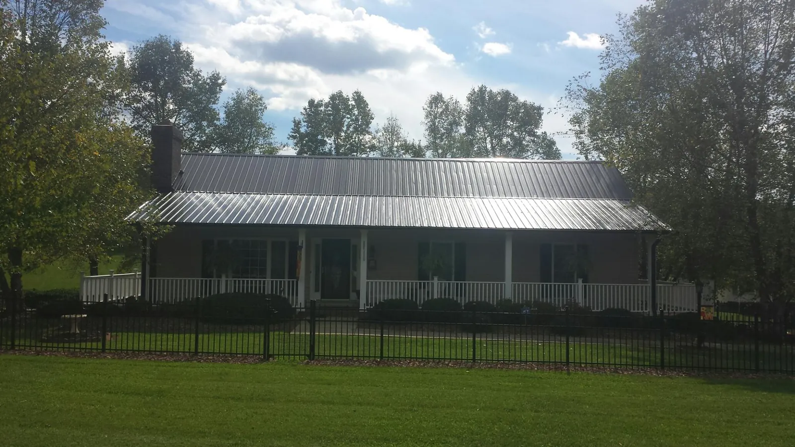 Gray metal roof on a brick ranch with a full width front porch — Gutter Guard Installation work by our crew in Lulu