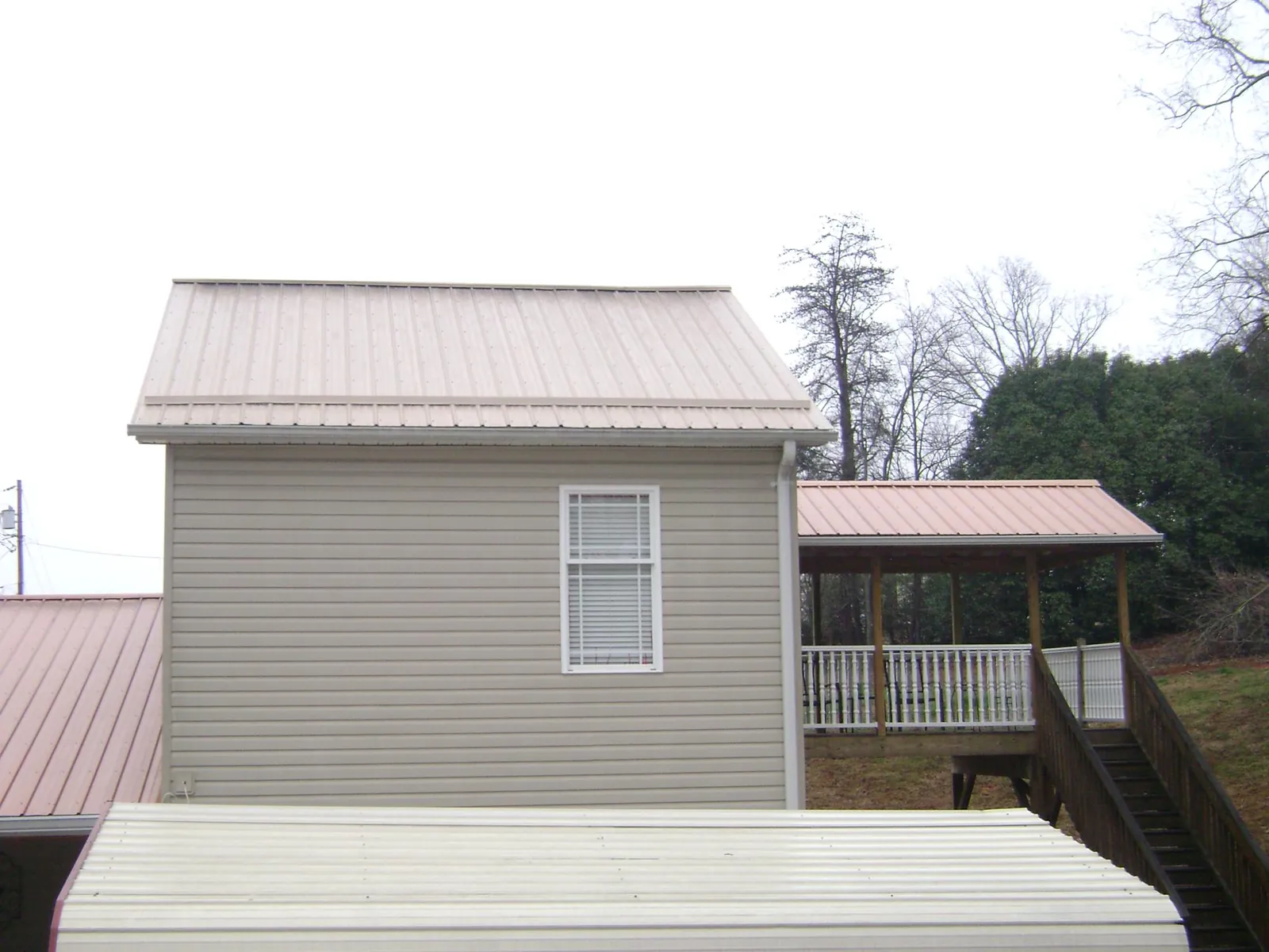 Tan metal roofs on a two story addition and attached porch, from a Roof Replacement job in Lulu