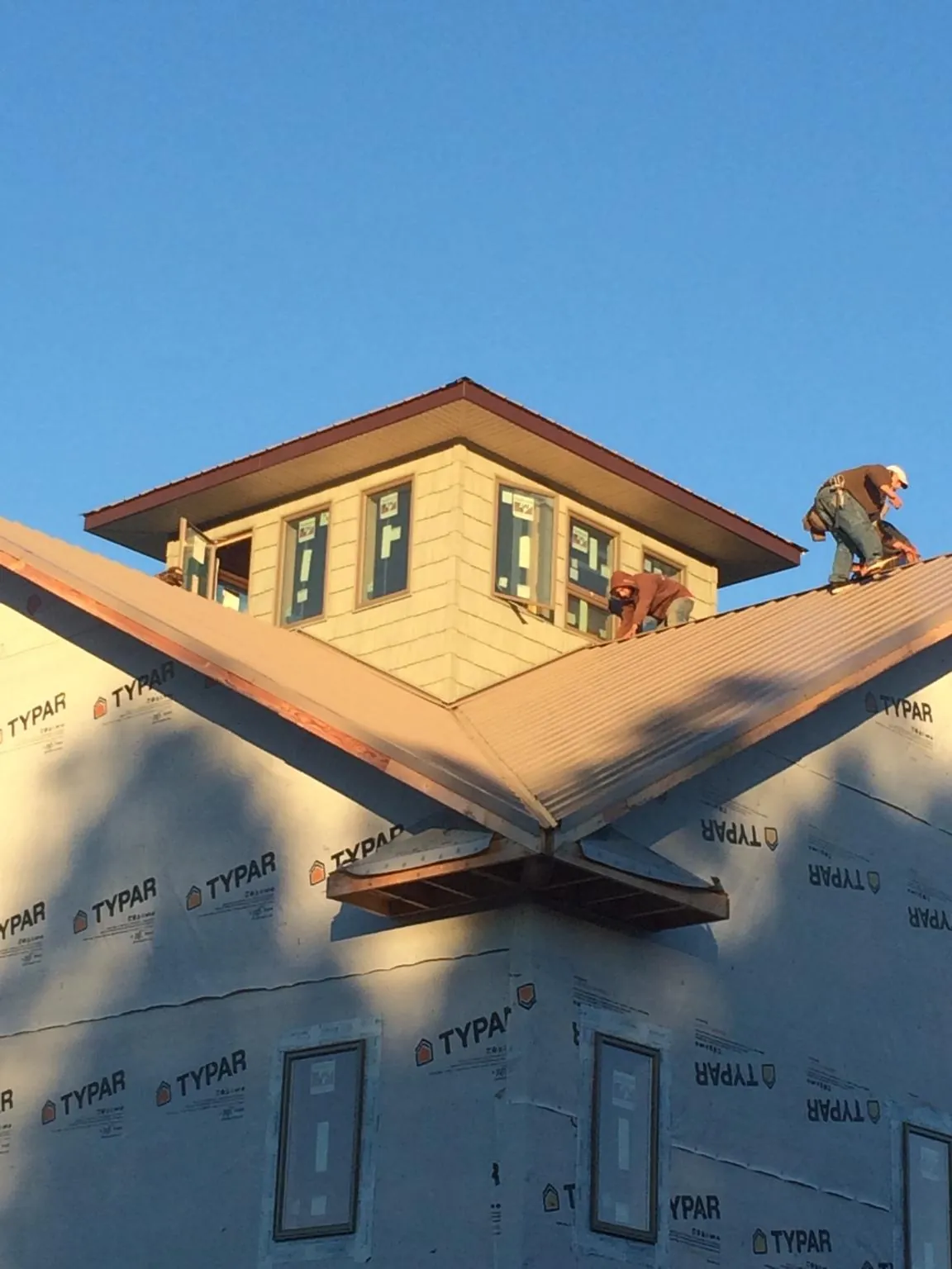 Roofers working around a rooftop cupola on a new metal roof at sunset — Roof Waterproofing in Lulu by Roofing Brothers